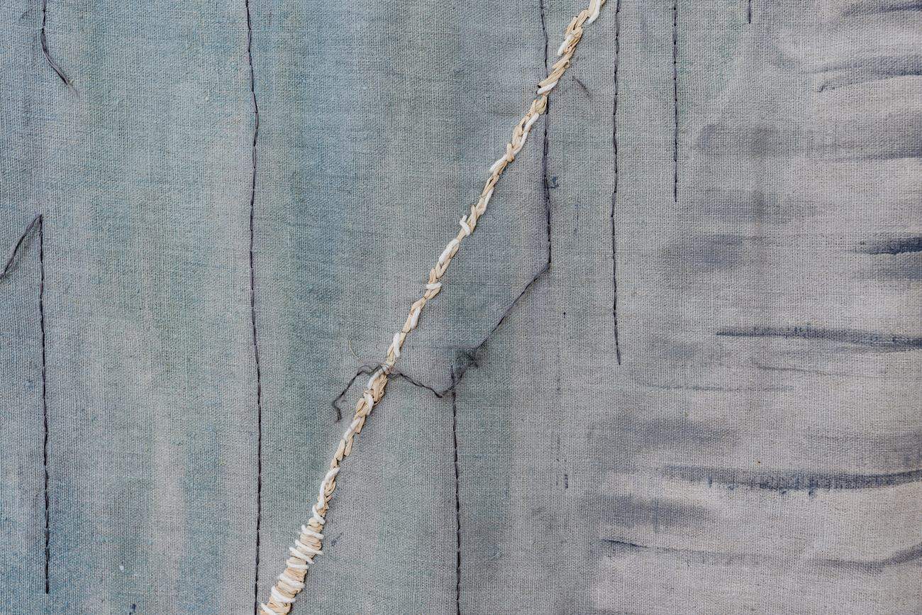 Detalhe da linha de palha costurada sobre linho azul, obra Insustentável, de Bia Távora